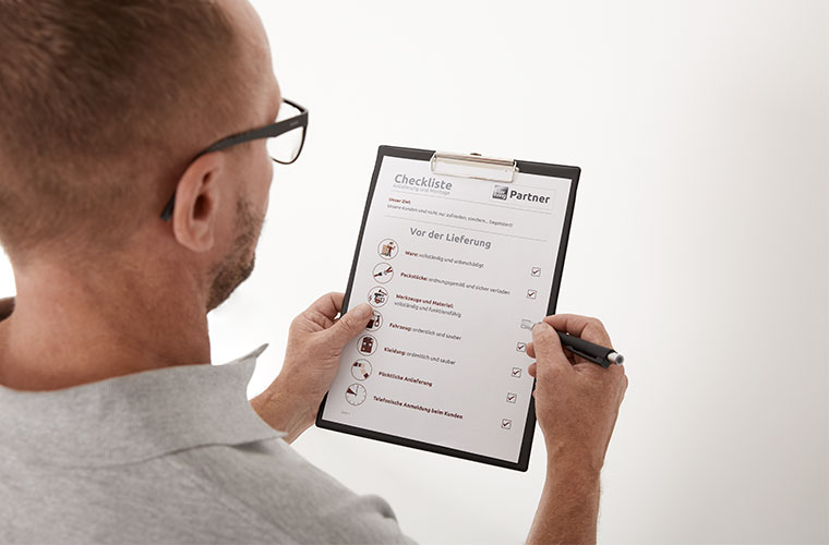 Mann schaut auf seine Checkliste.