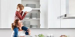 Kind hilft Mutter Teller aus hohem Schrank zu holen.